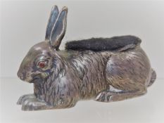 An Edwardian silver pin cushion rabbit with red cabochon stone set eyes, probably ruby