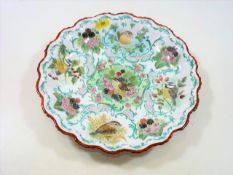 A hand painted dish with crimped rim depicting var