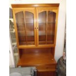 A modern glazed display cabinet with drawers & cup