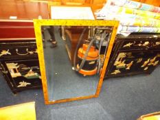 A decorative mirror with a burr maple style frame