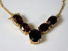A 14ct gold necklace with integrated garnet within