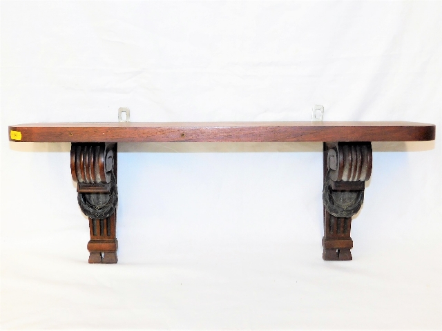 An antique mahogany shelf with gadrooned supports