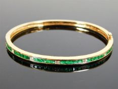 A 14ct gold diamond & emerald bangle with princess cut stones