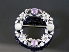 A white metal brooch set with amethyst & carved moonstone