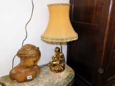 A gilded figurative lamp base with shade