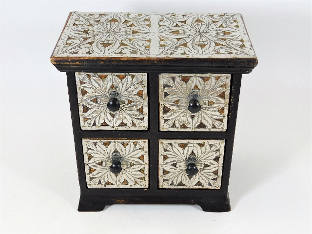 A small chest of drawers decorated in white metal