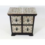 A small chest of drawers decorated in white metal