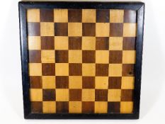 An early 20thC. chess board with lacquered frame