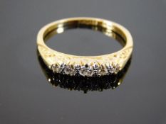 An 18ct gold ring set with five diamonds on scroll