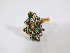 A yellow metal ring set with diamonds & emeralds