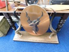 A large copper gong framed by kudu horns