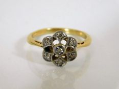 A yellow metal daisy ring set with diamonds