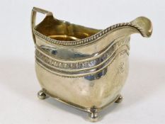 A Georgian silver cream jug on four ball feet
