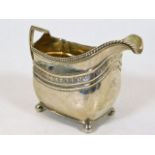 A Georgian silver cream jug on four ball feet