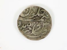 An antique white metal Asian coin, possibly Indian
