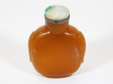 A 19thC. Chinese amber hard stone snuff bottle with carved sides & jade topped white metal stopper &