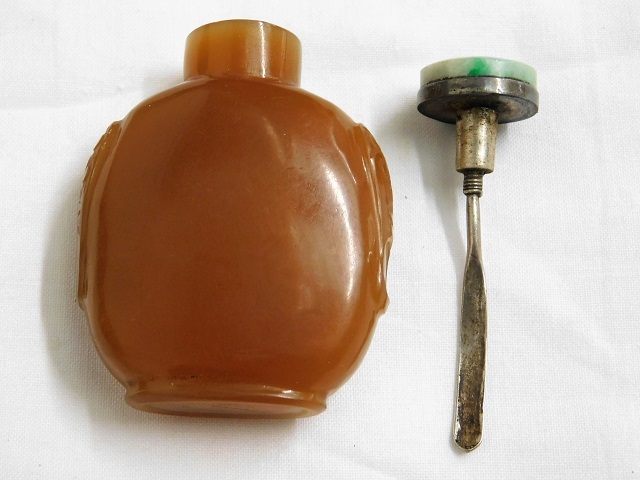 A 19thC. Chinese amber hard stone snuff bottle with carved sides & jade topped white metal stopper & - Image 2 of 3