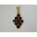 A yellow metal pendant set with garnets