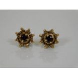 A pair of yellow metal earrings set with garnet