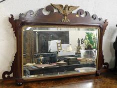 An antique mahogany mirror with gilt eagle decor