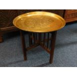 A brass Benares table with folding legs