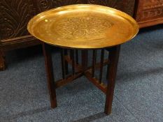 A brass Benares table with folding legs