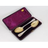 A pair of cased silver plated spoons with gilded b