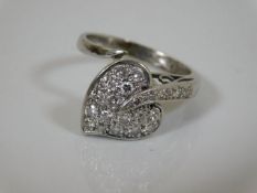 A white metal ring of heart shape set with diamond