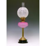 Victorian oil lamp having a pink satin glass reservoir, reeded pillar and circular foot on a black