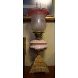 Early 20th Century oil lamp having opaque pink glass reservoir and square domed cast iron base