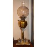 Brass oil lamp having a reeded Corinthian column, the triangular base having figural decoration