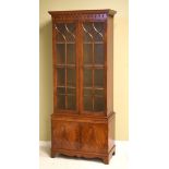Reproduction mahogany cabinet bookcase, the upper section fitted four shelves enclosed by a pair