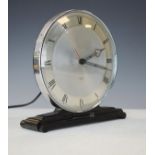 Art Deco design mantel clock having a chrome framed dial with Roman numerals and standing on a black