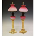 Pair of late 19th/early 20th Century candlestick oil lamps, each having a wrythened pink satin glass