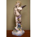 German porcelain figure depicting Cupid, standing before a floral column, his bow concealed behind