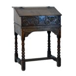 Antique oak slope front Bible box and stand having a foliate carved frieze and standing on bobbin