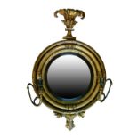 Regency circular gilt framed convex wall mirror having a stylised foliate pediment and fitted with