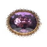 Oval amethyst coloured faceted stone brooch set within a gilt metal seed pearl border Condition: