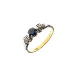 Dress ring having central sapphire coloured stone, flanked each side by a diamond, the white metal