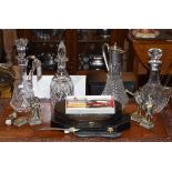 Two cut glass decanters, two claret jugs, various silver plated cutlery and four cast brass figures,