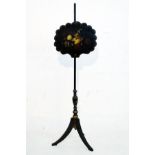 Victorian ebonised polescreen the shaped oval panel with painted foliate decoration, standing on a