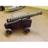 A 19th century miniature bronze cannon mounted on stepped wooden carriage with 4 wooden wheels.