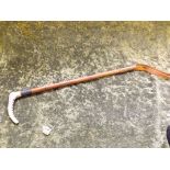 A bamboo riding crop with horn handle and silver band.