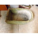 A 19th century carved stone sarcophagus shaped water trough with drainage hole.