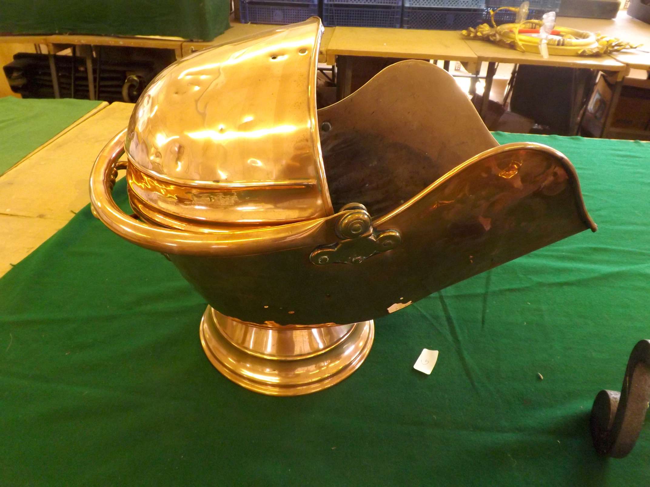 A large antique copper coal helmet with bonnet top with shovel.