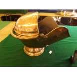 A large antique copper coal helmet with bonnet top with shovel.