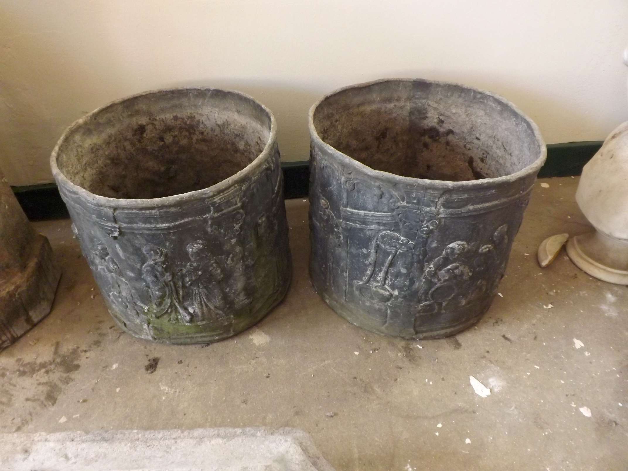 A pair of unusual cylindrical lead planter with embossed classical decoration and pierced base,