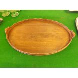 An Edwardian oval mahogany tea tray with integral handles, 22 1/2" x 14" wide.