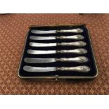 A boxed set of six dessert knives with silver handles.