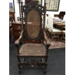 A 19th century high backed carver chair being heavily carved with cane back and seat.